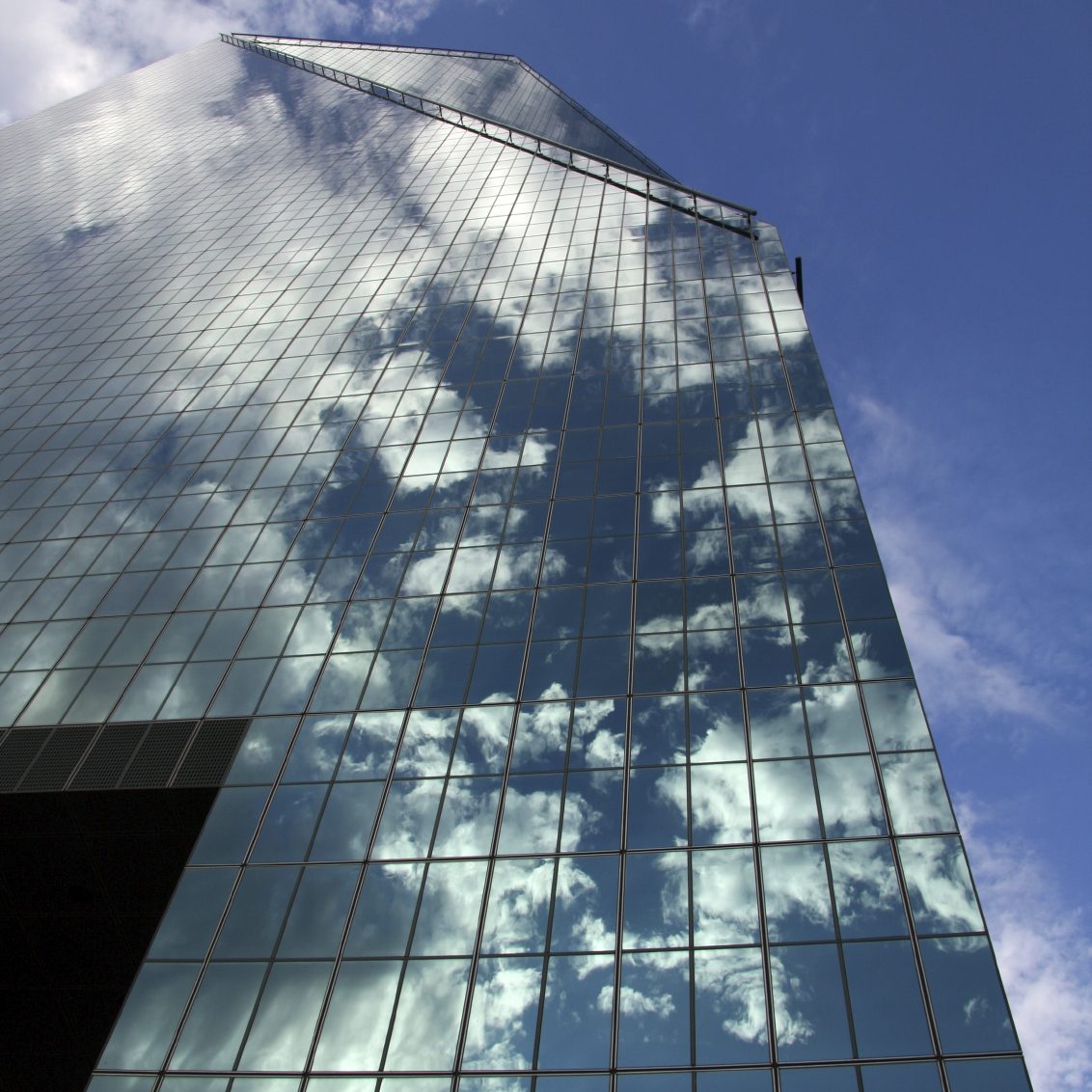 Reflejo de nubes en la fachada de un edificio de vidrio.